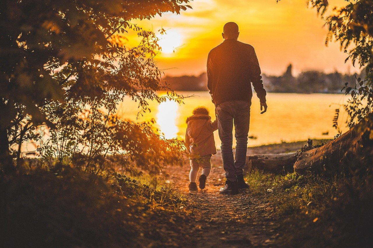Man walking with child at sunset near lake